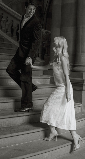 Couple celebrating a special night out, walking hand in hand down a grand staircase